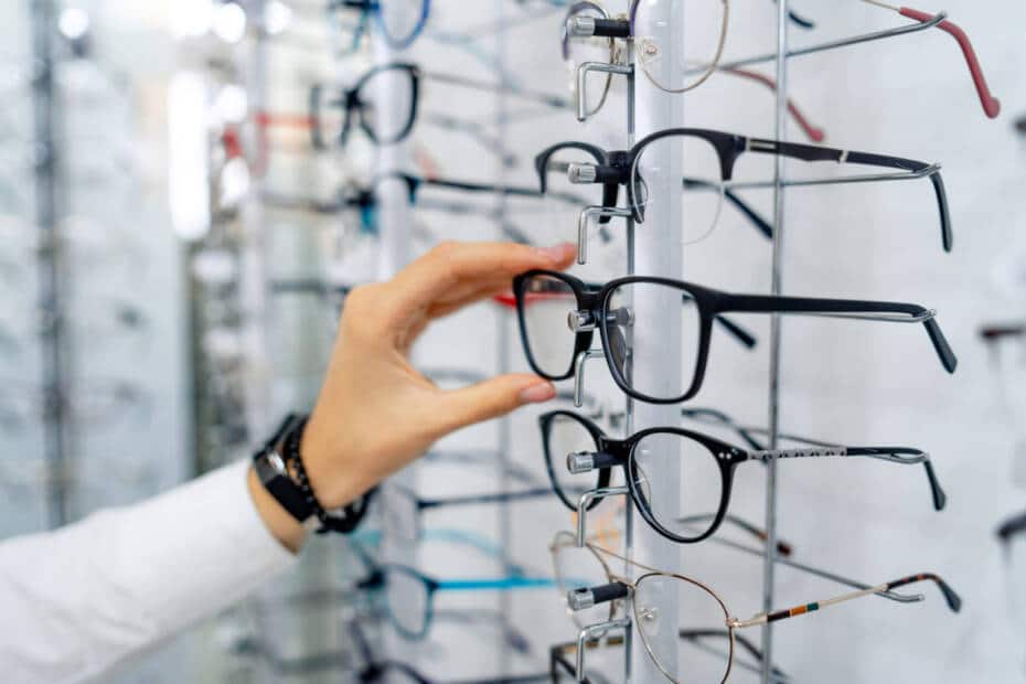 Hand greift sich eine Brille aus einem Schaukasten