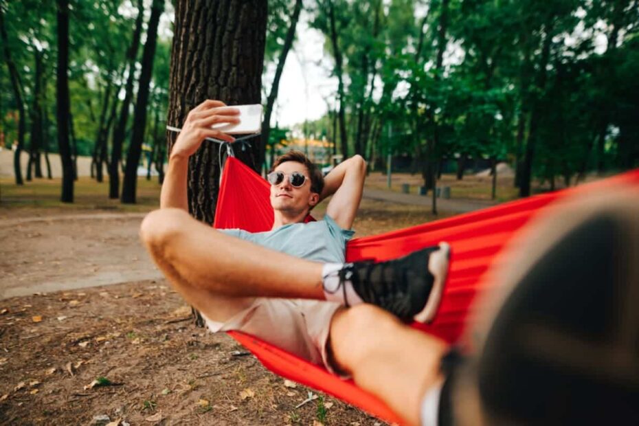 junger Mann in Hängematte mit Handy