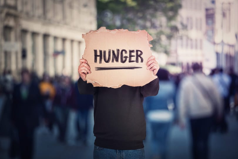 Mann in Menschenmenge mit Schild "Hunger"