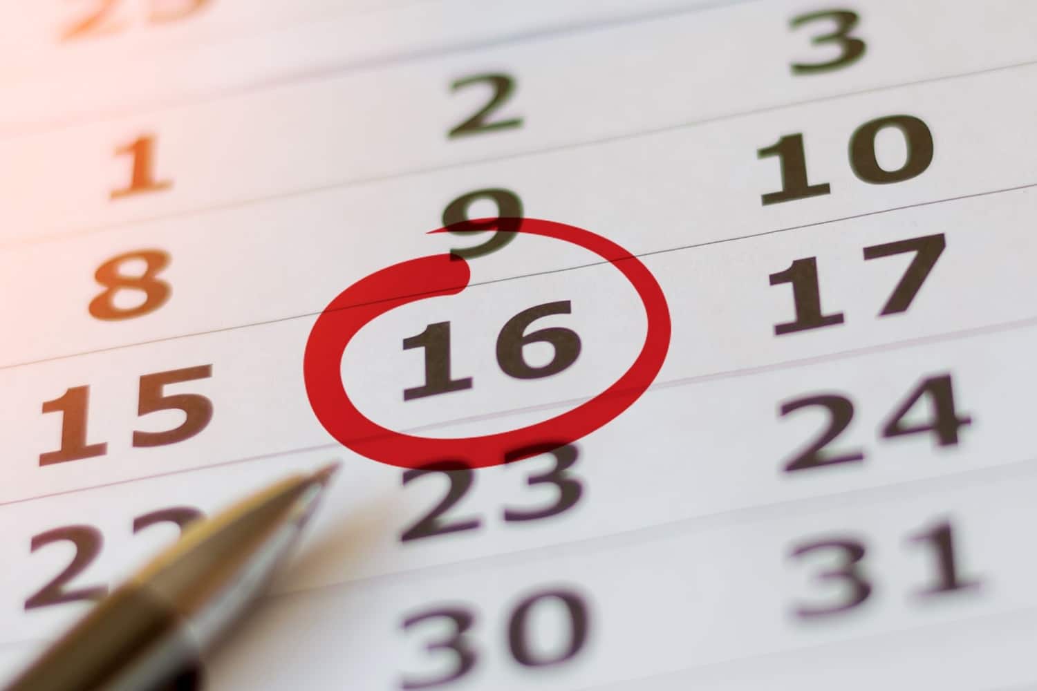 Kugelschreiber auf Kalender-Blatt, ein Tag ist rot umkreist, markiert