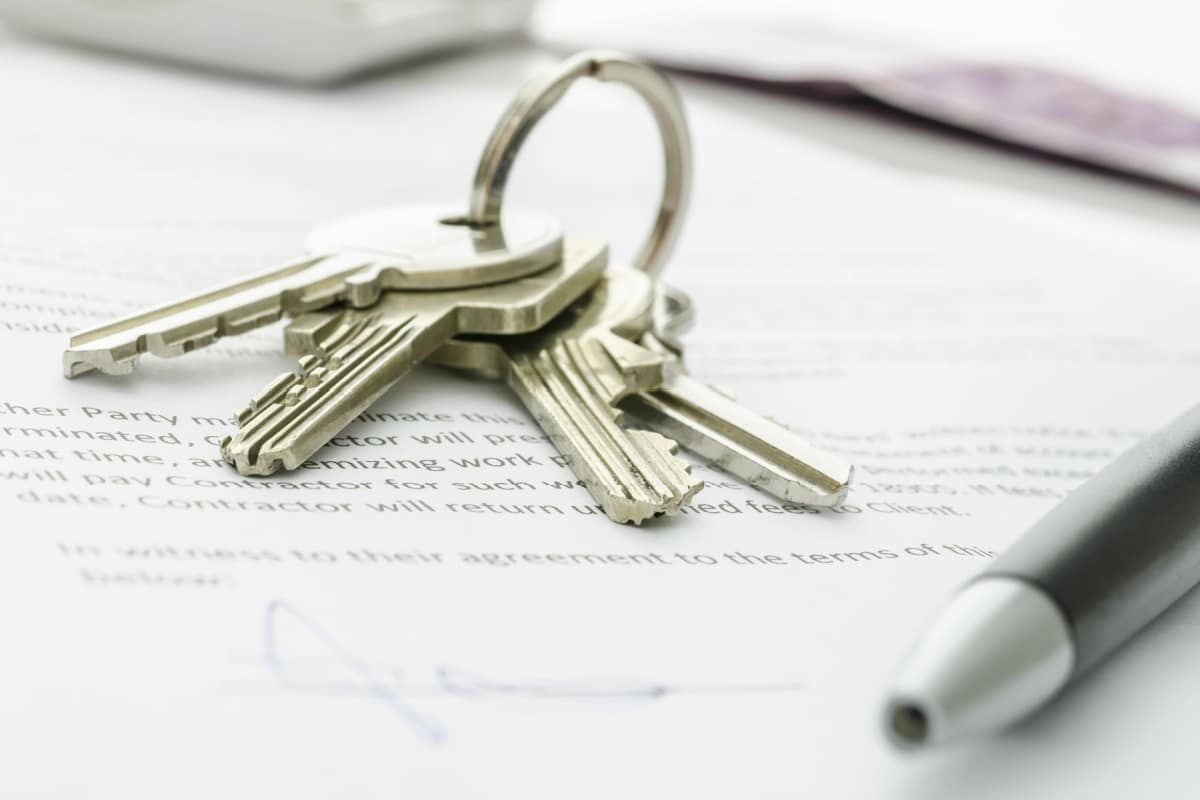 Wohnungsschlüssel und Kugelschreiber liegen auf einem unterschriebenen Mietvertrag, im Hintergrund Euro-Banknoten.