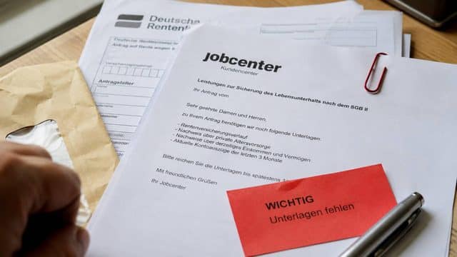 Jobcenter-Schreiben mit fehlenden Renten-Unterlagen und rotem Hinweis auf einem Schreibtisch
