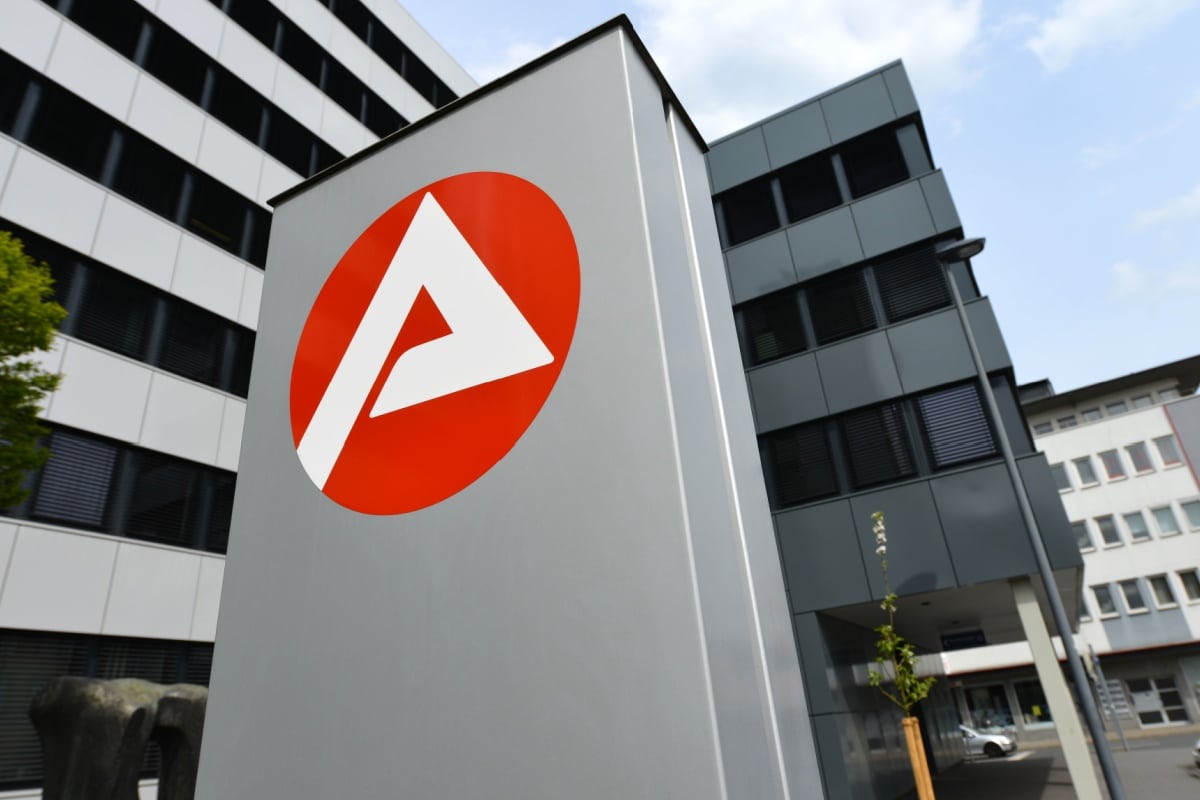 Schild mit Logo vor dem Eingang eines Jobcenters