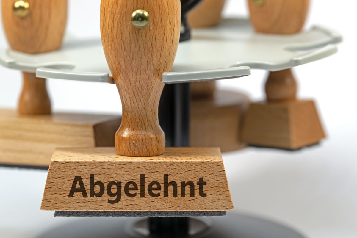 Symbolbild zur Ablehnung von Leistungen: Ein Holzstempel mit der Aufschrift "Abgelehnt" in einer Nahaufnahme.