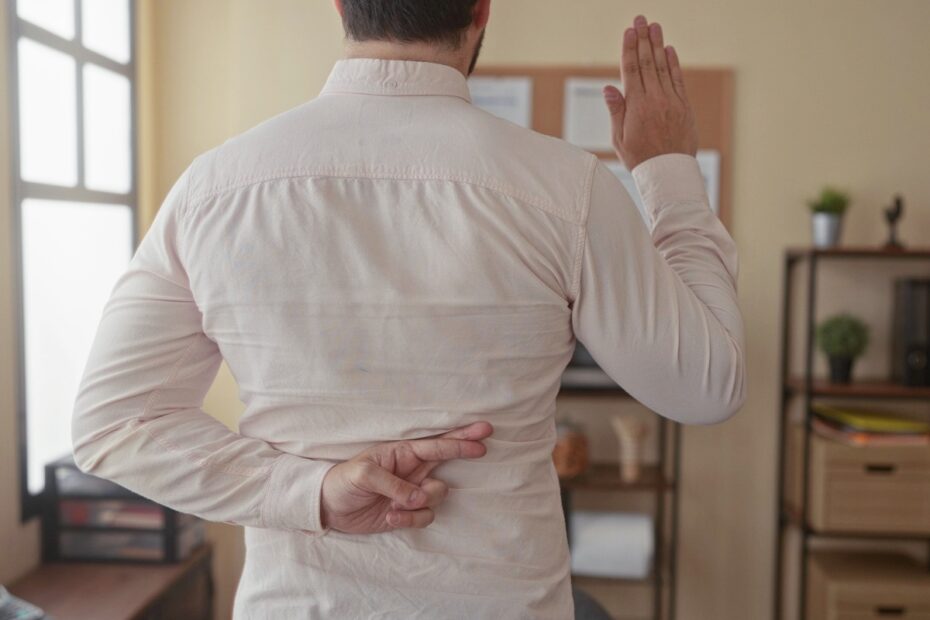 Symbolbild zum Scheinmietvertrag beim Bürgergeld: Ein Mann kreuzt beim Schwur heimlich die Finger hinter dem Rücken.