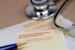 Stethoskop und Kugelschreiber auf gelber Krankmeldung