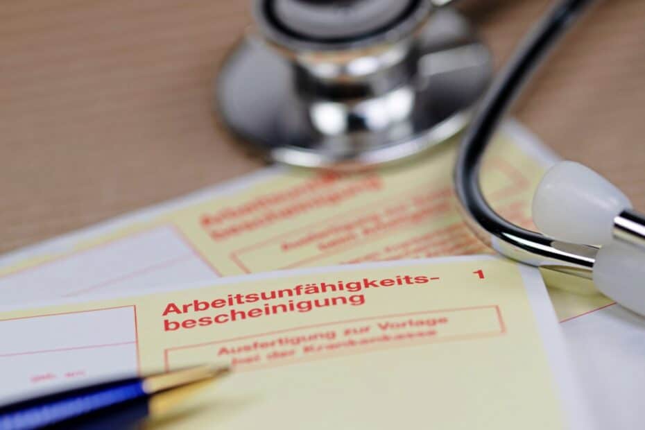 Stethoskop und Kugelschreiber auf gelber Krankmeldung