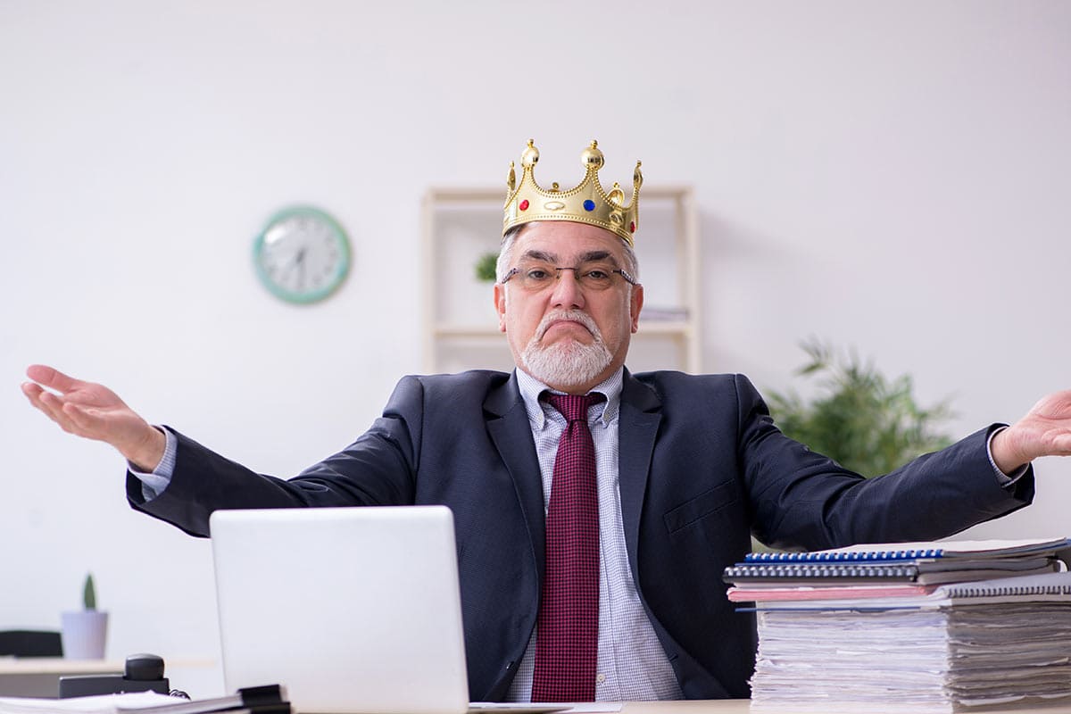 Beamter im Büro mit einer goldenen Krone auf Kopf - Behördenwillkür