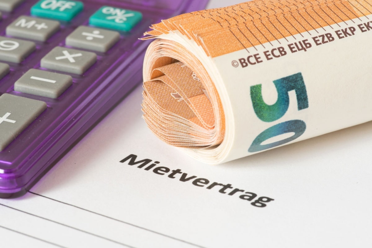 Rolle 50 Euro Scheine und Taschenrechner auf einem Mietvertrag, Symbolisch für Wohnkosten im Bürgergeld