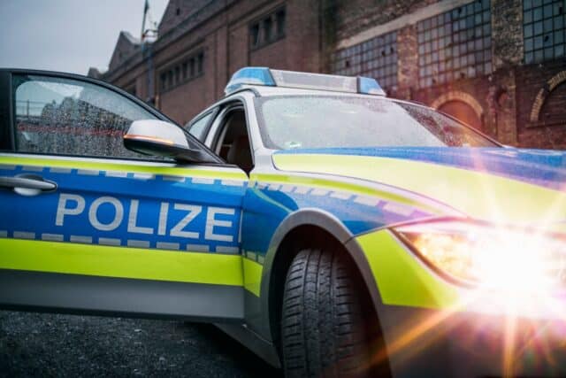 Polizeiauto mit Blaulicht vor Industriegebäude