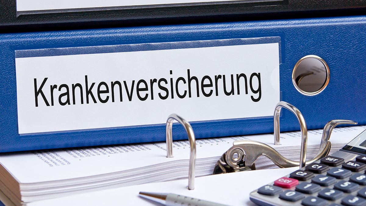 Aktenordner mit Aufschrift Krankenversicherung und Taschenrechner