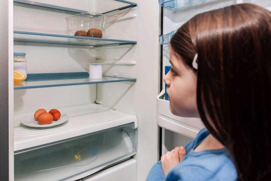 Junges Mädchen schaut in fast leeren Kühlschrank