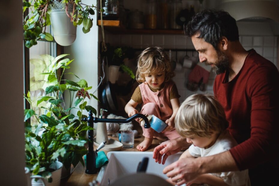 Besorgter Vater mit zwei Kindern macht Hausarbeit mit 2 Kindern