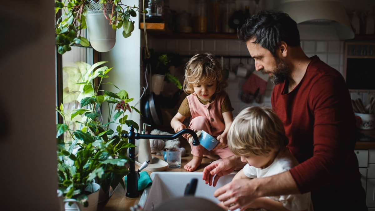 Besorgter Vater mit zwei Kindern macht Hausarbeit mit 2 Kindern