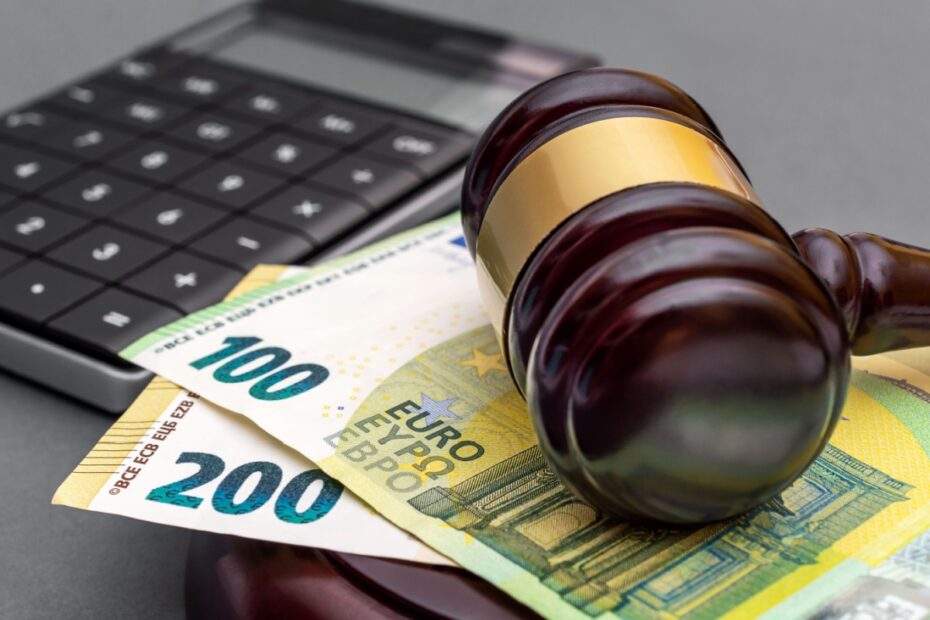 Richterhammer auf Geldscheinen neben Taschenrechner.