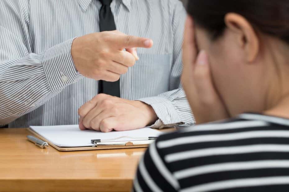 Mahnender Finger zeigt auf Frau, die ihr Gesicht in den Händen vergräbt