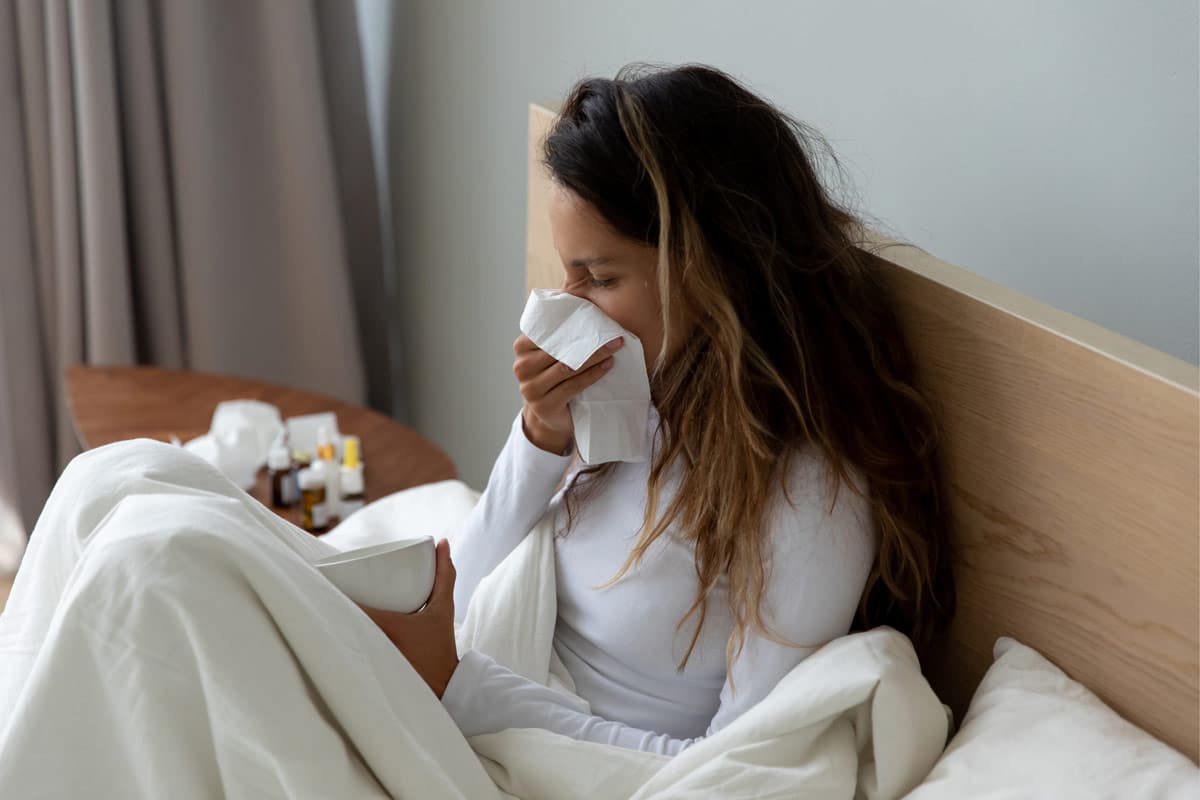 frau mit Erkältung im Bett zu Hause