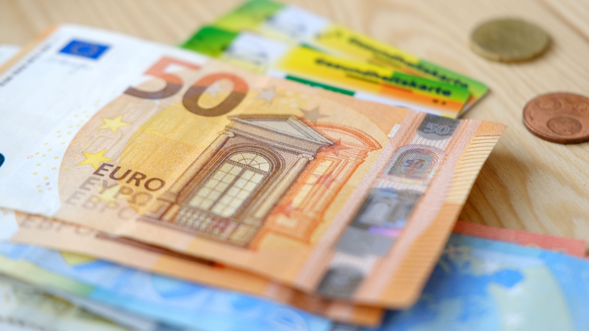 Geldscheine liegen auf Gesundheitskarte, symbolisch für Kostenübernahme der Krankenversicherung