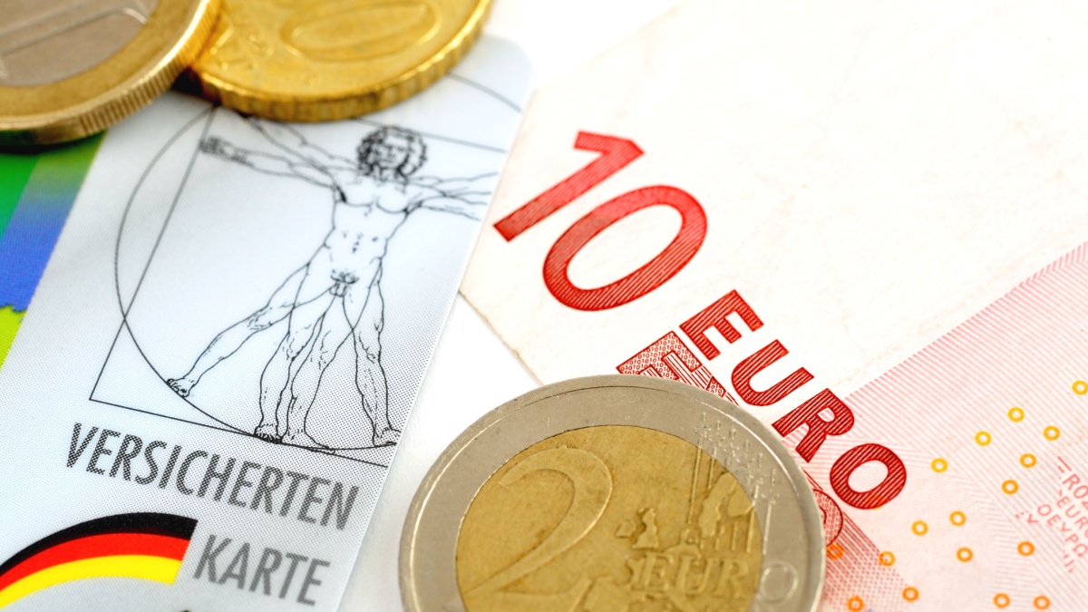 Versichertenkarte und Euro-Scheine. Symbolisiert die Kostenübernahme der Krankenversicherung beim Bürgergeld durch das Jobcenter.