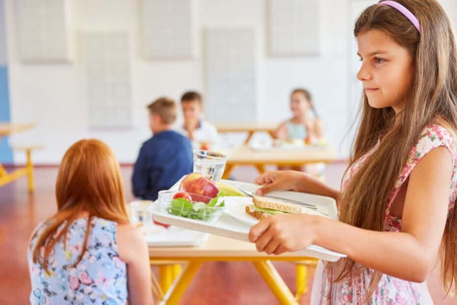 Junges Mädchen holt Essen in der Schulkantine, Symbol für Leistungen zur Bildung und Teilhabe