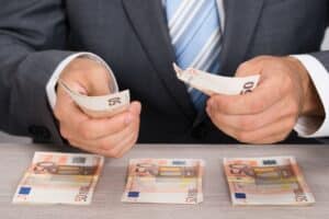 Mann im Anzug legt mehrere Stapel von 50 Euro Scheinen