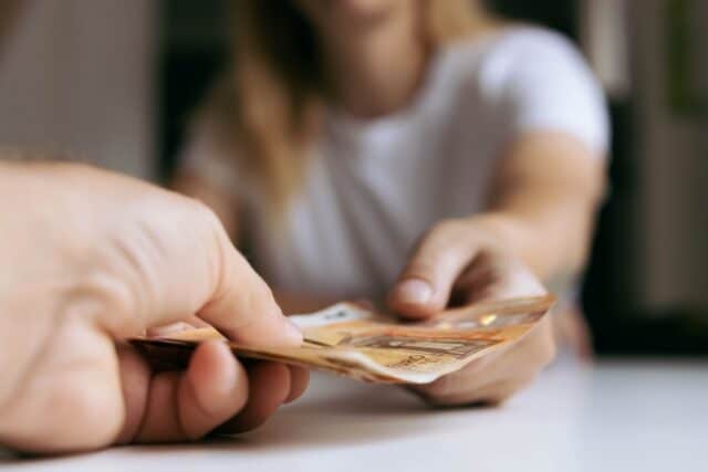 Nahaufnahme, eine Person überreicht einer anderen Euro-Geldscheine, symbolisch für Zuwendung