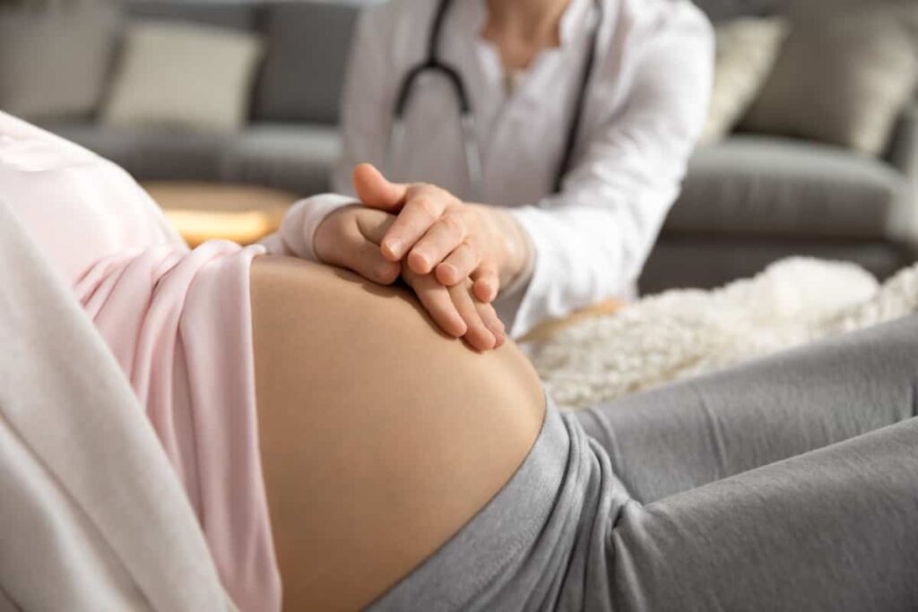 Ärztin untersucht den Bauch einer schwangeren Frau