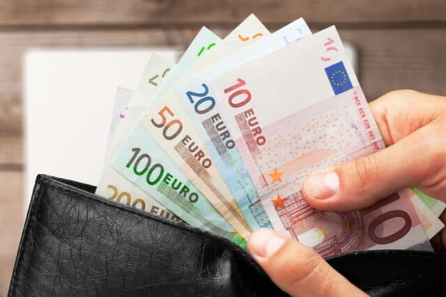 Hände holen Geldscheine aus Geldbörse