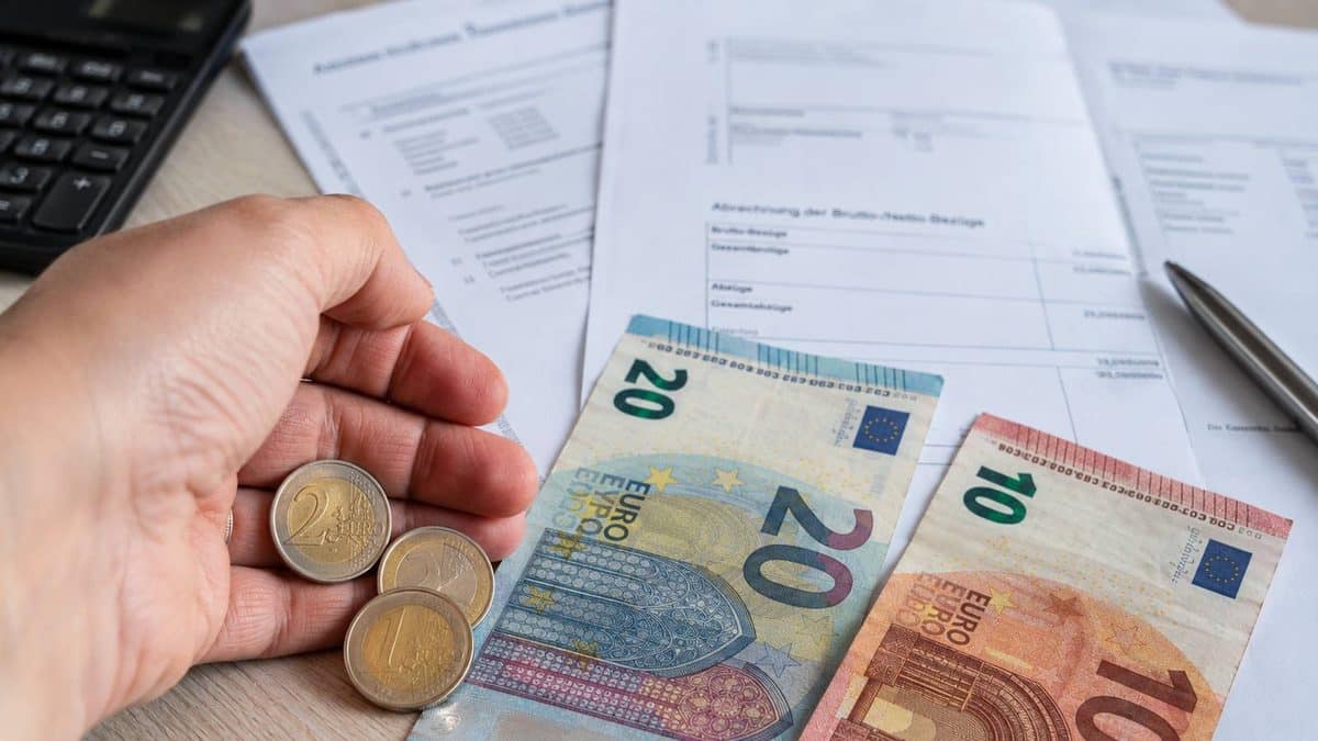 Minijobber zählt Geld neben einer Lohnabrechnung und einem Taschenrechner
