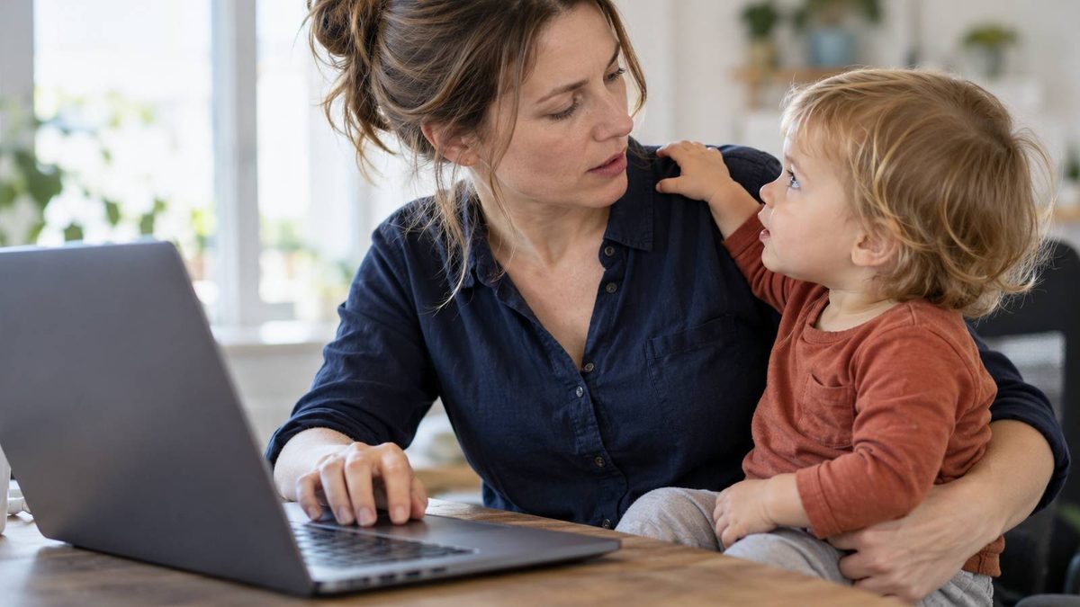 Mutter arbeitet am Laptop, während ihr Kleinkind auf ihrem Schoß sitzt.