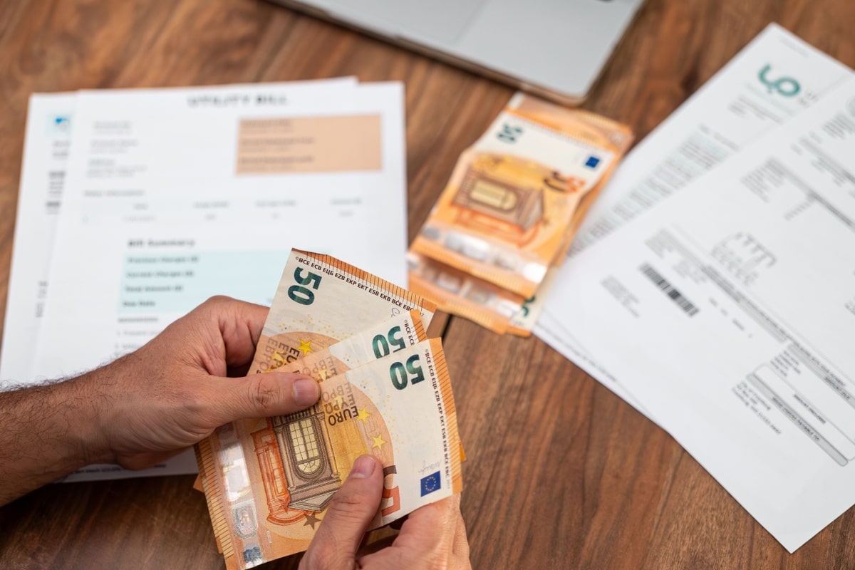 Mann zählt Geldscheine, auf dem Tisch liegen Unterlagen der Nebenkostenabrechnung