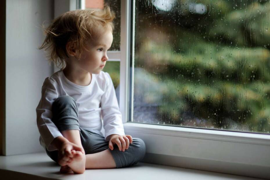 Trauriges Kleinkind schaut aus dem Fenster