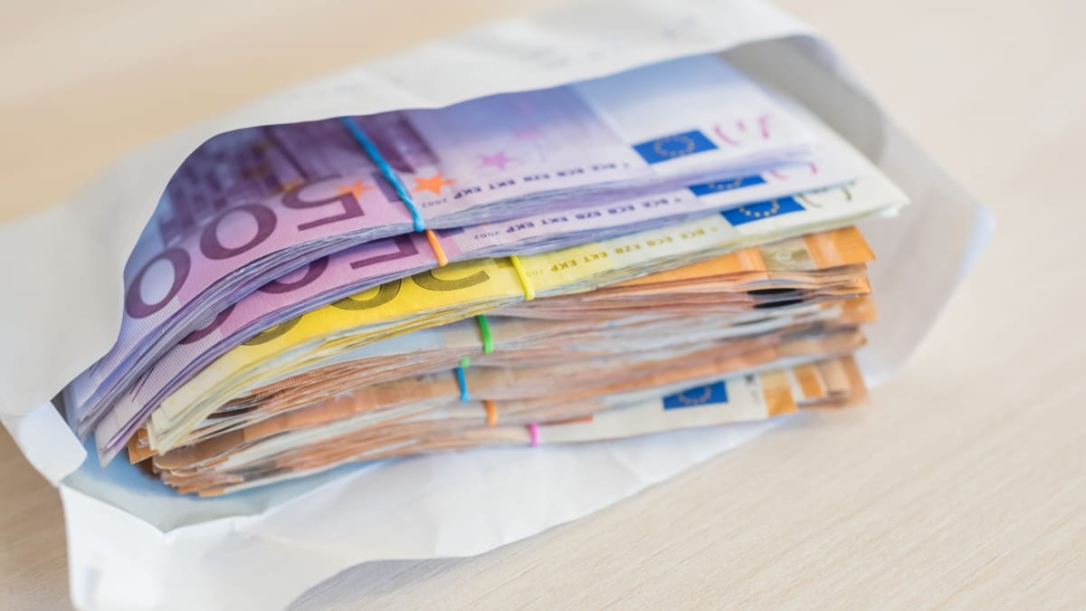 Nahaufnahme eines Umschlags, gefüllt mit einem großen Stapel von Euro-Banknoten, symbolisiert illegalen Bürgergeld-Betrug und Profit.
