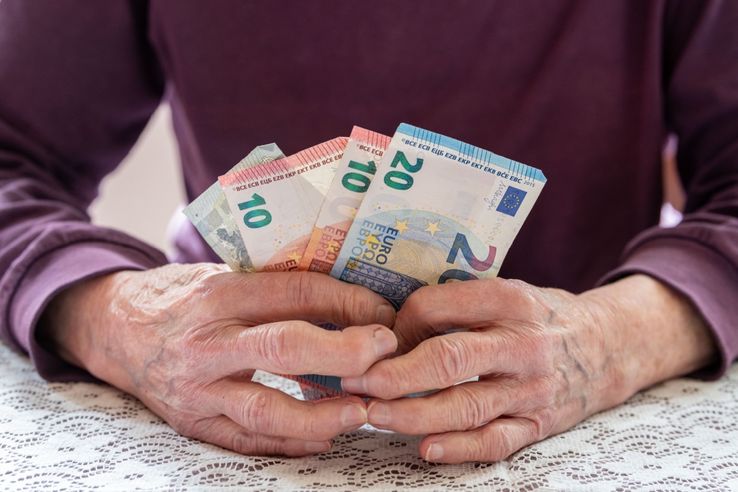 Rentnerin mit ein paar Euro-Geldscheinen in den Händen, symbolisch für niedrige Rente