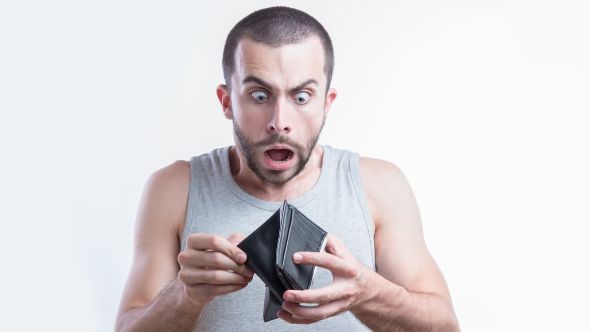 Mann schaut schockiert in leeren Geldbeutel - Symbol für finanzielle Notlage und fehlendes Bürgergeld.