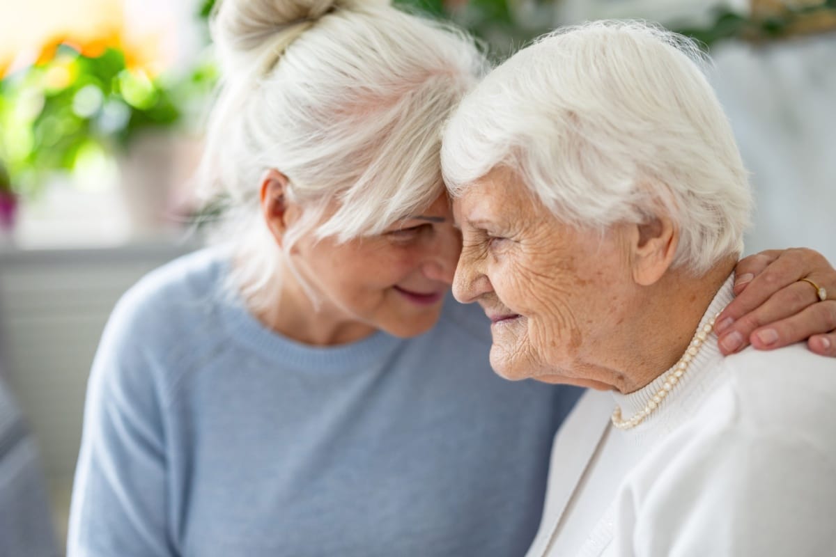 Ältere Frau wird liebevoll von Angehöriger unterstützt – symbolische Darstellung häuslicher Pflege und Pflegegeld im Zusammenhang mit Bürgergeld.