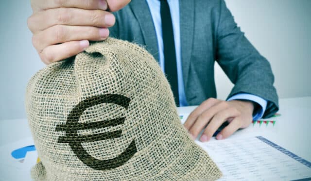 Anzugträger hält Münzsack mit Eurozeichen in der Hand