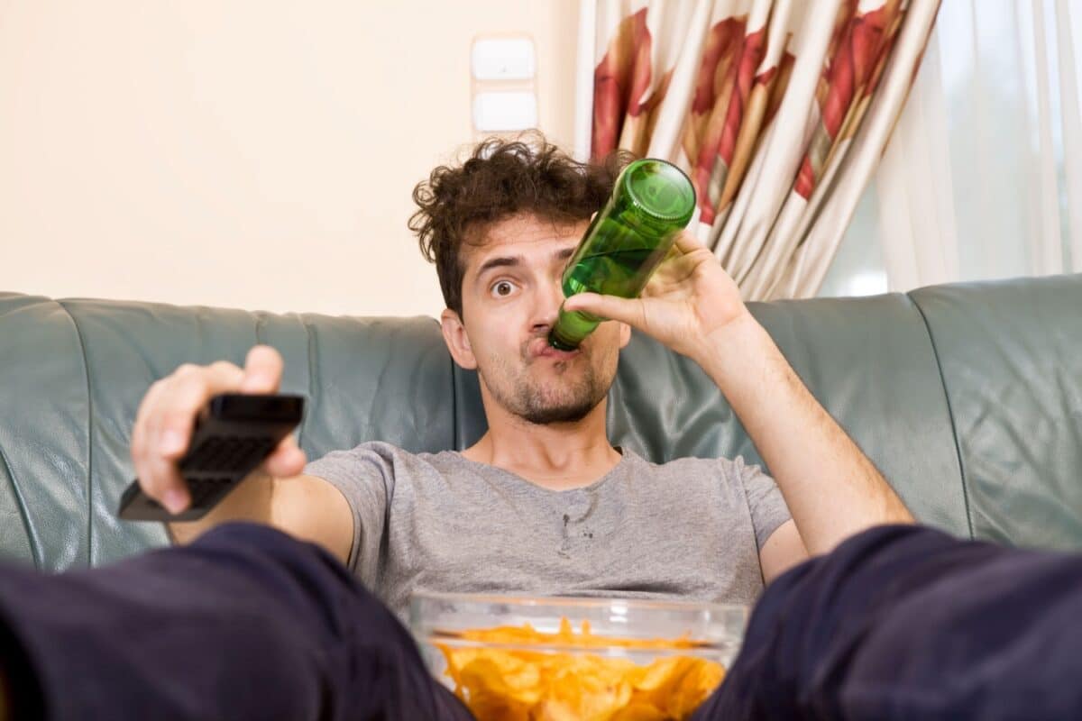 Mann mit Chips und Getränkt vor dem Fernseher