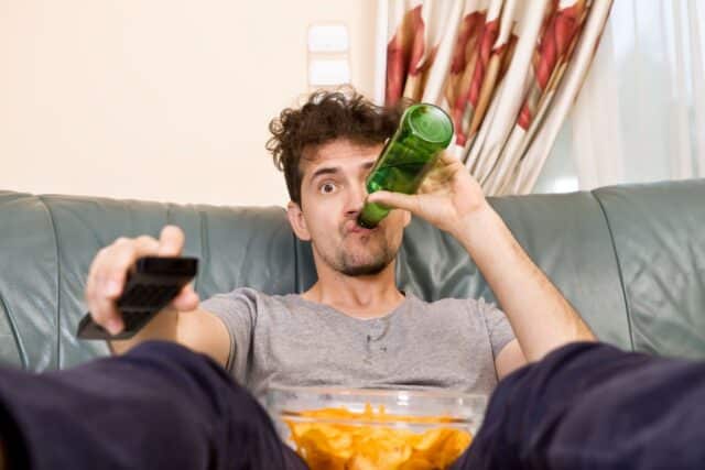 Mann mit Chips und Getränkt vor dem Fernseher