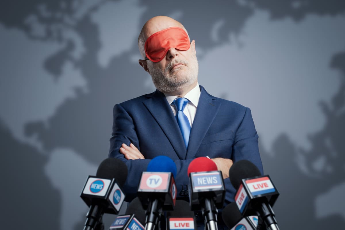 Politiker bei Pressekonferenz mit Schlafmaske