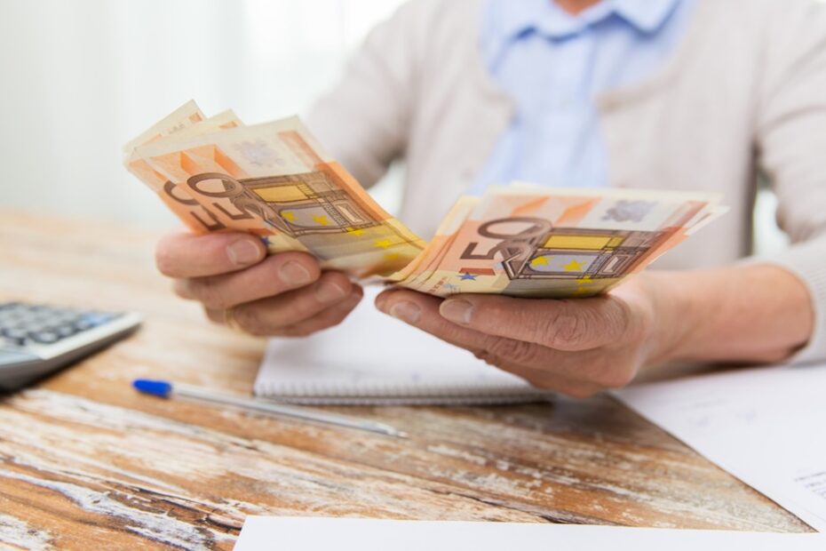 Rentnerin mit Stapel Geld in der Hand zählt ihre Rentenerhöhung 2026