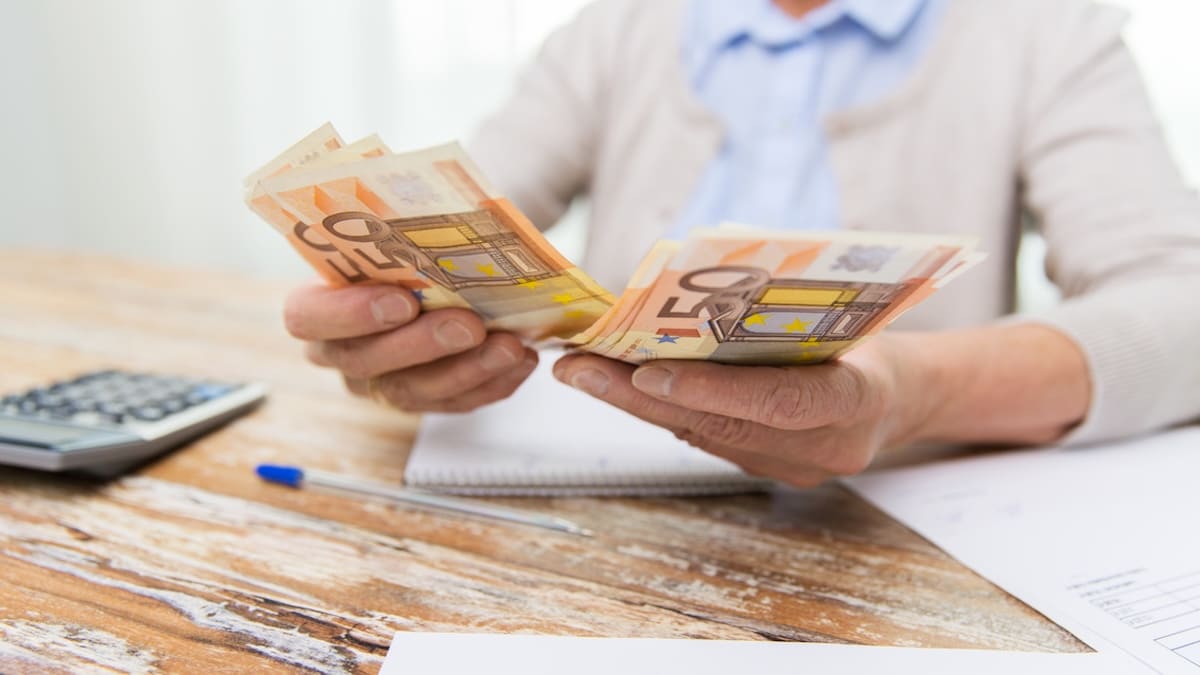 Rentnerin mit Stapel Geld in der Hand zählt ihre Rentenerhöhung 2026