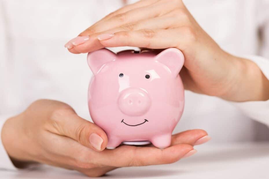 Nahaufnahme: Hände halten schützend ein Sparschwein, symbolisch für Schonvermögen beim Bürgergeld