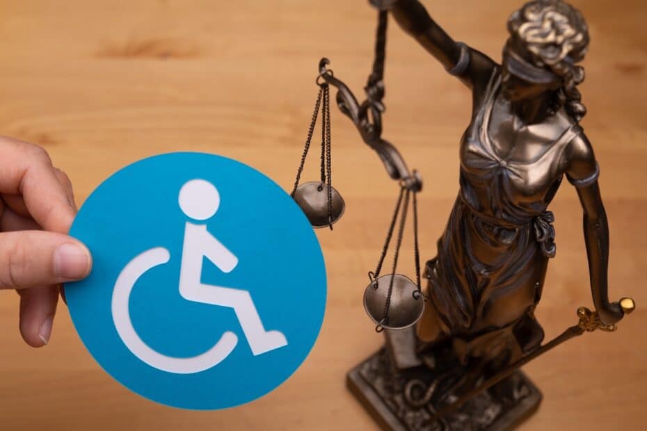 Justitia Bronze Figut und Frauenhand hält Behinderten Abzeichen