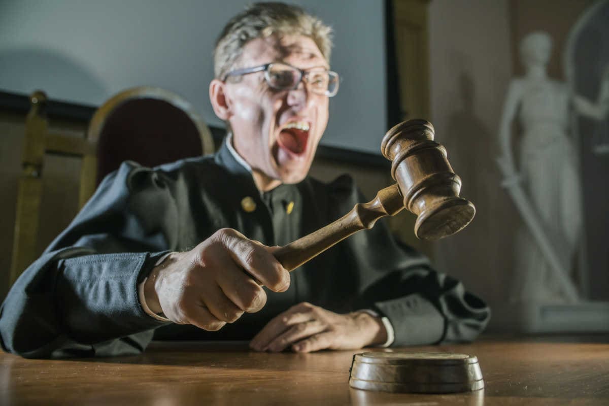 Wütender Richter schlägt mit Richterhammer auf den Tisch