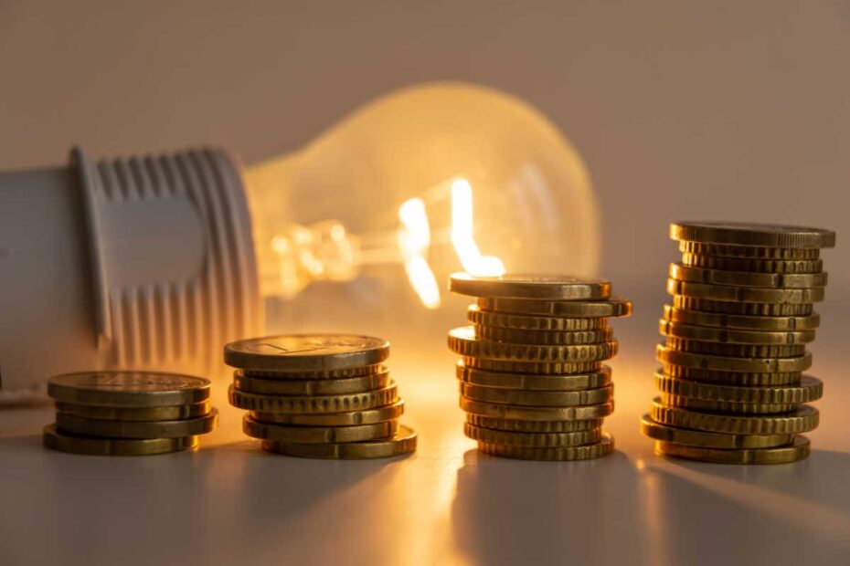 Leuchtende Glühbirne mit Euro-Münzen aufsteigend gestapelt als Symbol für Strompreise