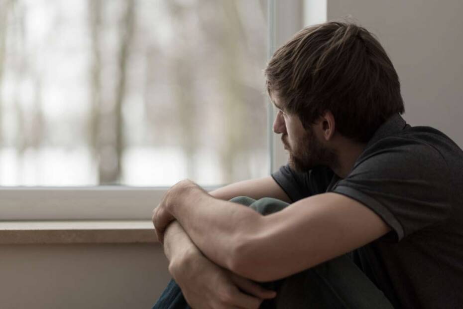 Trauriger Mann schaut aus dem Fenster