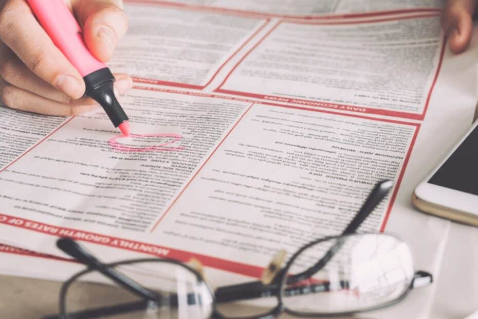 Hand kreist mit Textmarker Stellenanzeigen in der Zeitung ein