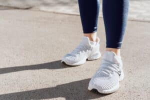 Symbolbild für den Mehrbedarf: Füße und weiße Schuhe, für die das Sozialgericht Hamburg einen Zuschuss zum Bürgergeld wegen krankheitsbedingtem Verschleiß genehmigt hat.