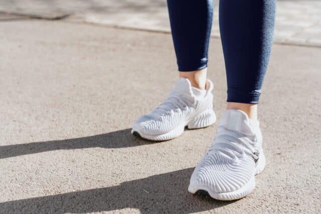 Symbolbild für den Mehrbedarf: Füße und weiße Schuhe, für die das Sozialgericht Hamburg einen Zuschuss zum Bürgergeld wegen krankheitsbedingtem Verschleiß genehmigt hat.